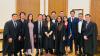 13 female and male members of Cambridge University Filipino Society wearing black university robes smiling for the camera while standing.