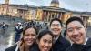 Four Filipino students in their 20s take a selfie in front of the National Gallery in London. They are all wearing black coats/jackets. 