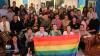A group of people sitting together with the Pride flag